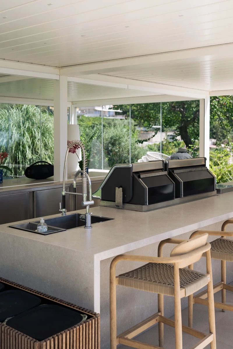 Cucina da esterno con isola con barbecue, lavandini e piano d'appoggio
