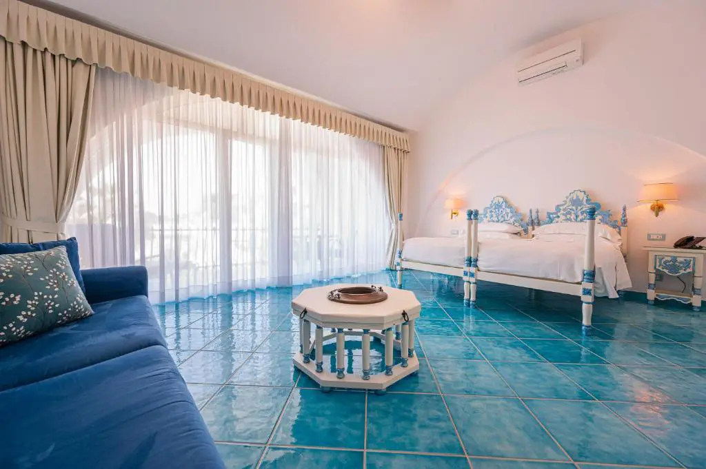 Camera hotel pavimento azzurro, divano blu e decorazioni azzurre
