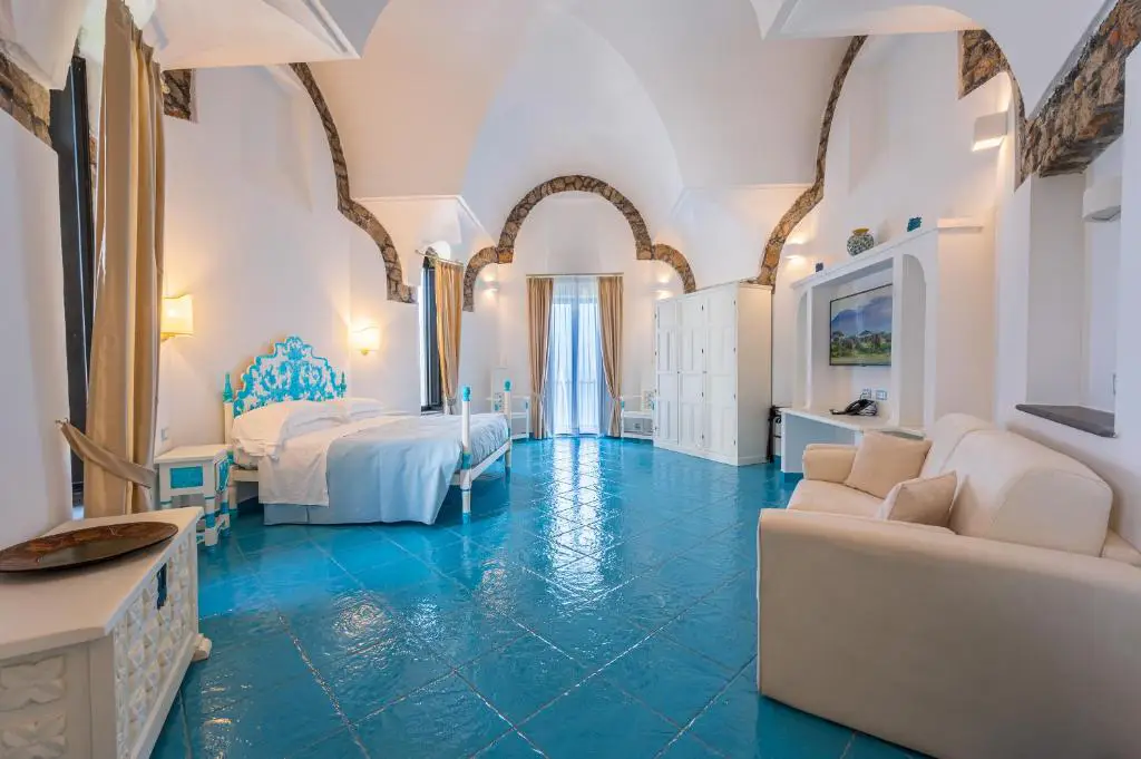 Camera hotel con pavimento azzurro e letto con dettagli azzurri