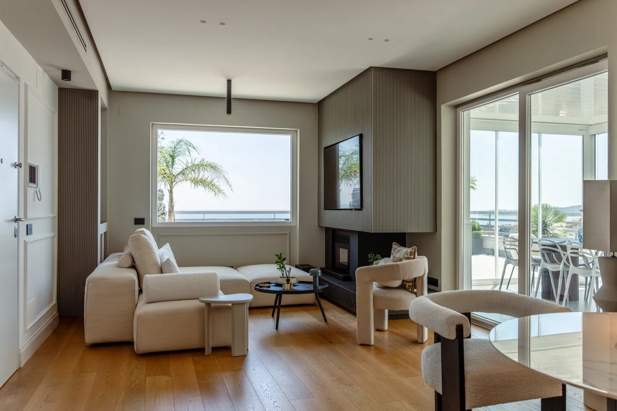 Zona living con divano in tessuto chiaro, parquet e camino