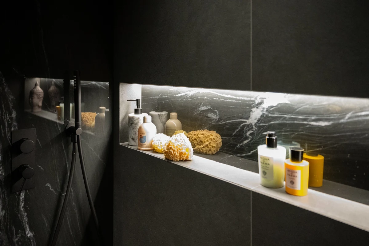 Dettaglio doccia walk in con nicchia illuminata e rivestimento in marmo nero