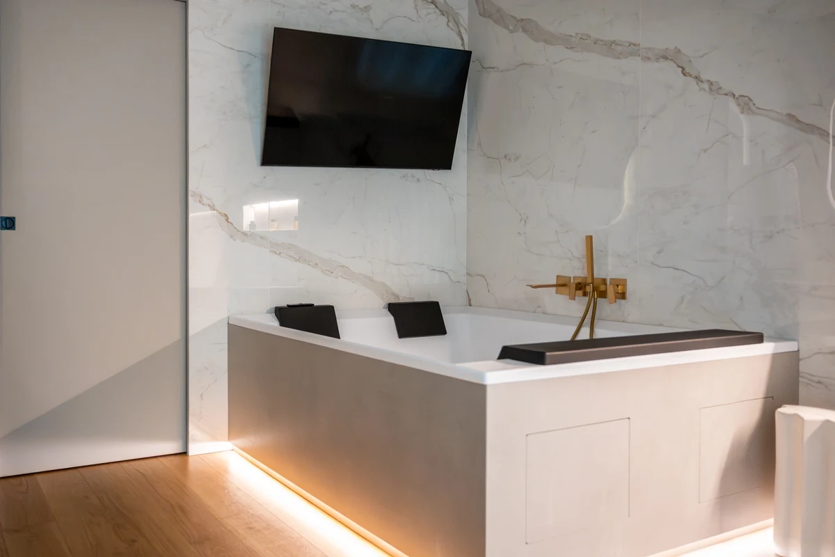 Vasca angolare con profili a led e parete in marmo