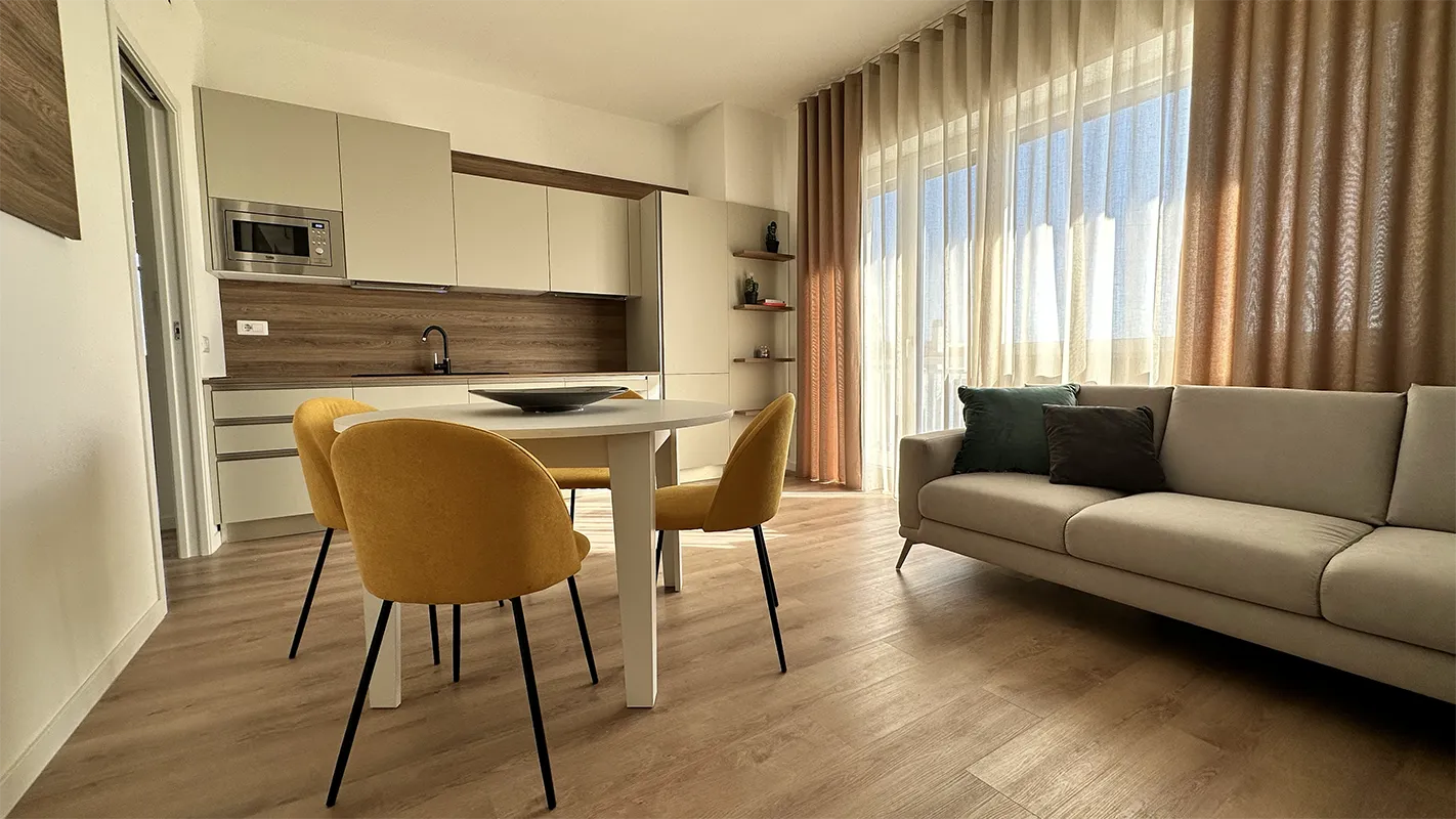 Cucina e sala da pranzo arredate in stile moderno con parquet e divano chiari