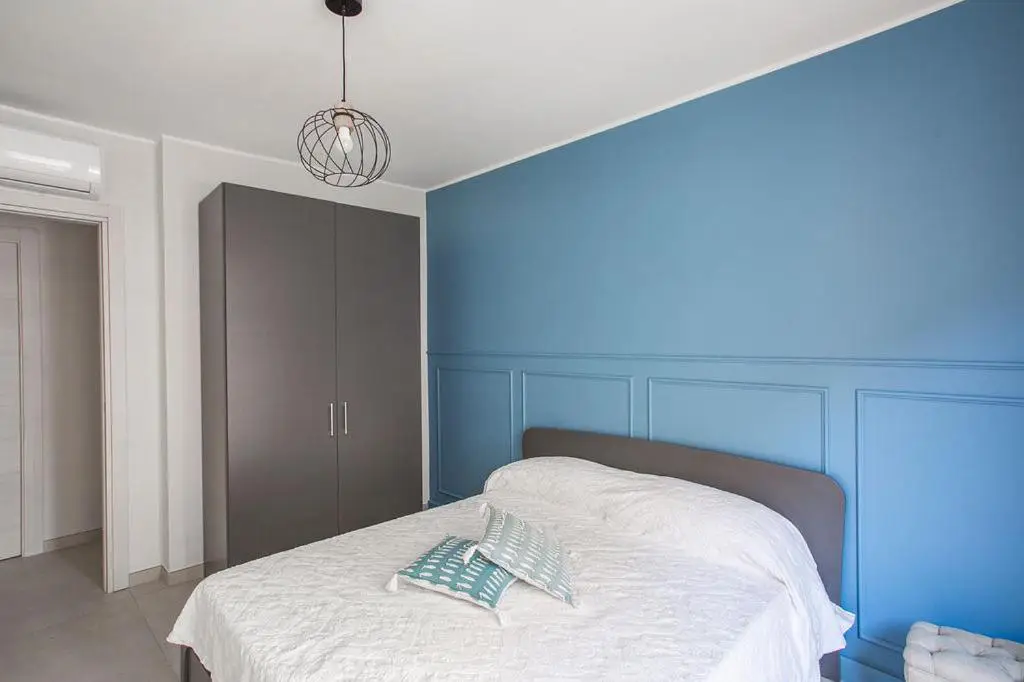 Camera da letto con parete con boiserie azzurra