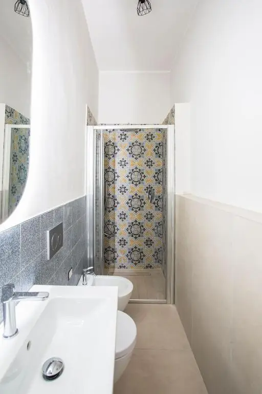 Prospettiva bagno con doccia incassata con piastrelle decorate con maioliche blu