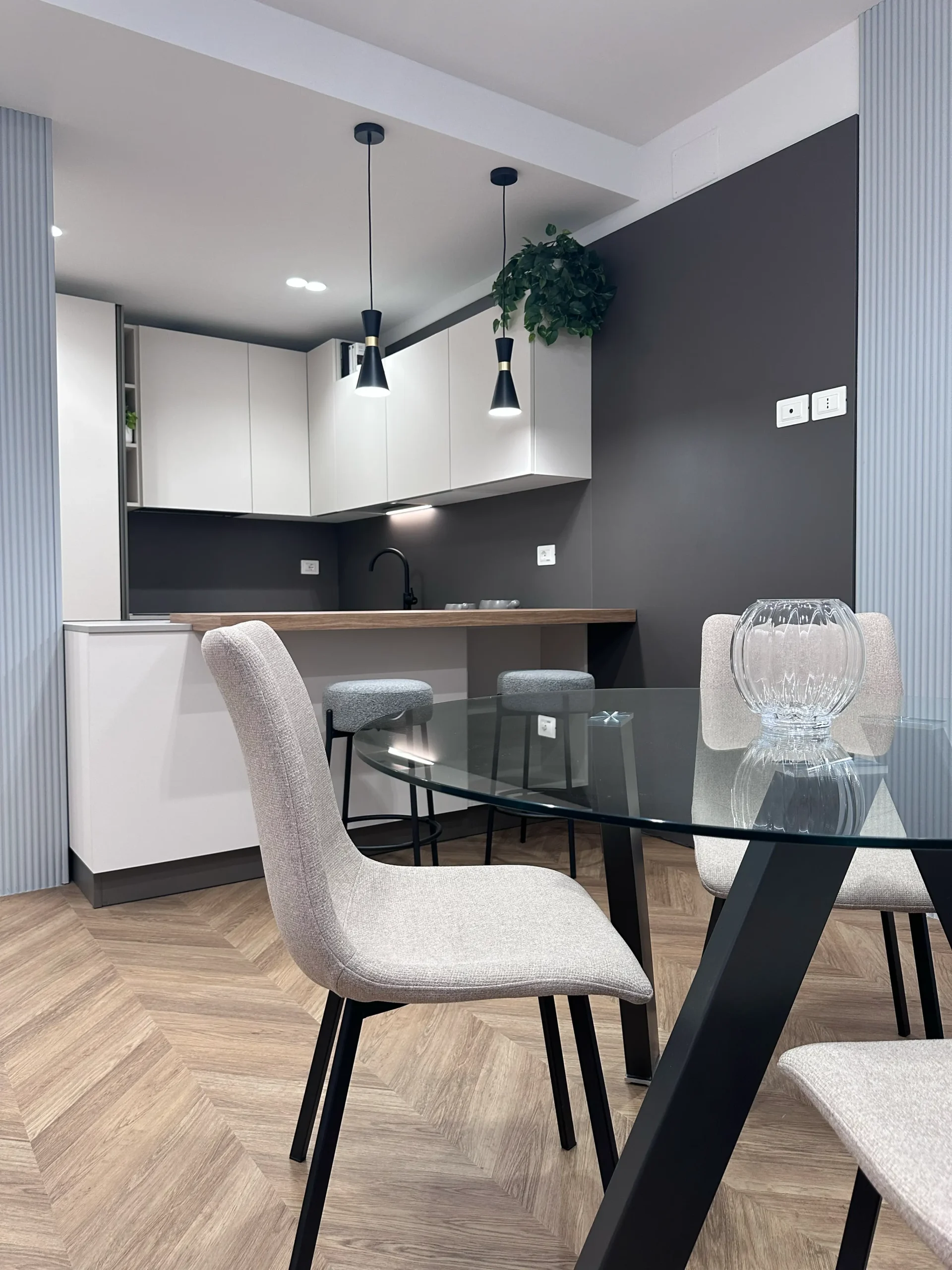 Cucina moderna con tavolo in vetro, poltroncine beige e parquet