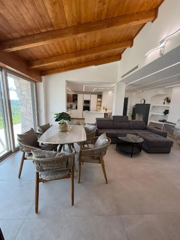 Sala da pranzo con tetto in legno, tavolo da pranzo in marmo bianco e poltrone grigie
