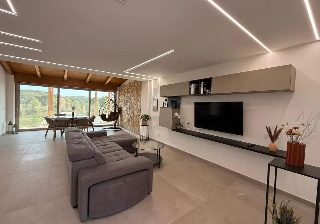 Zona living con divano grigio e parete tv beige