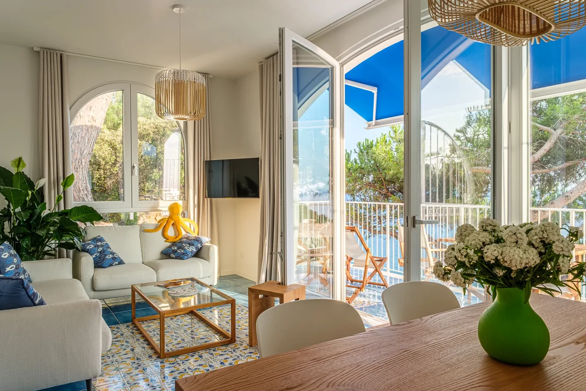 Visuale sala di una casa vacanza con tavolo rustico e divano angolare bianco