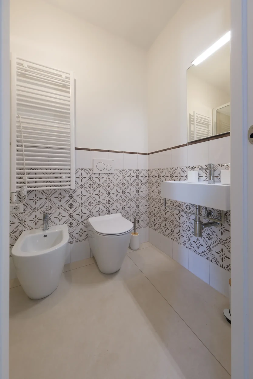 Sanitari bianchi a terra, lavabo sospeso e termoarredo bianco