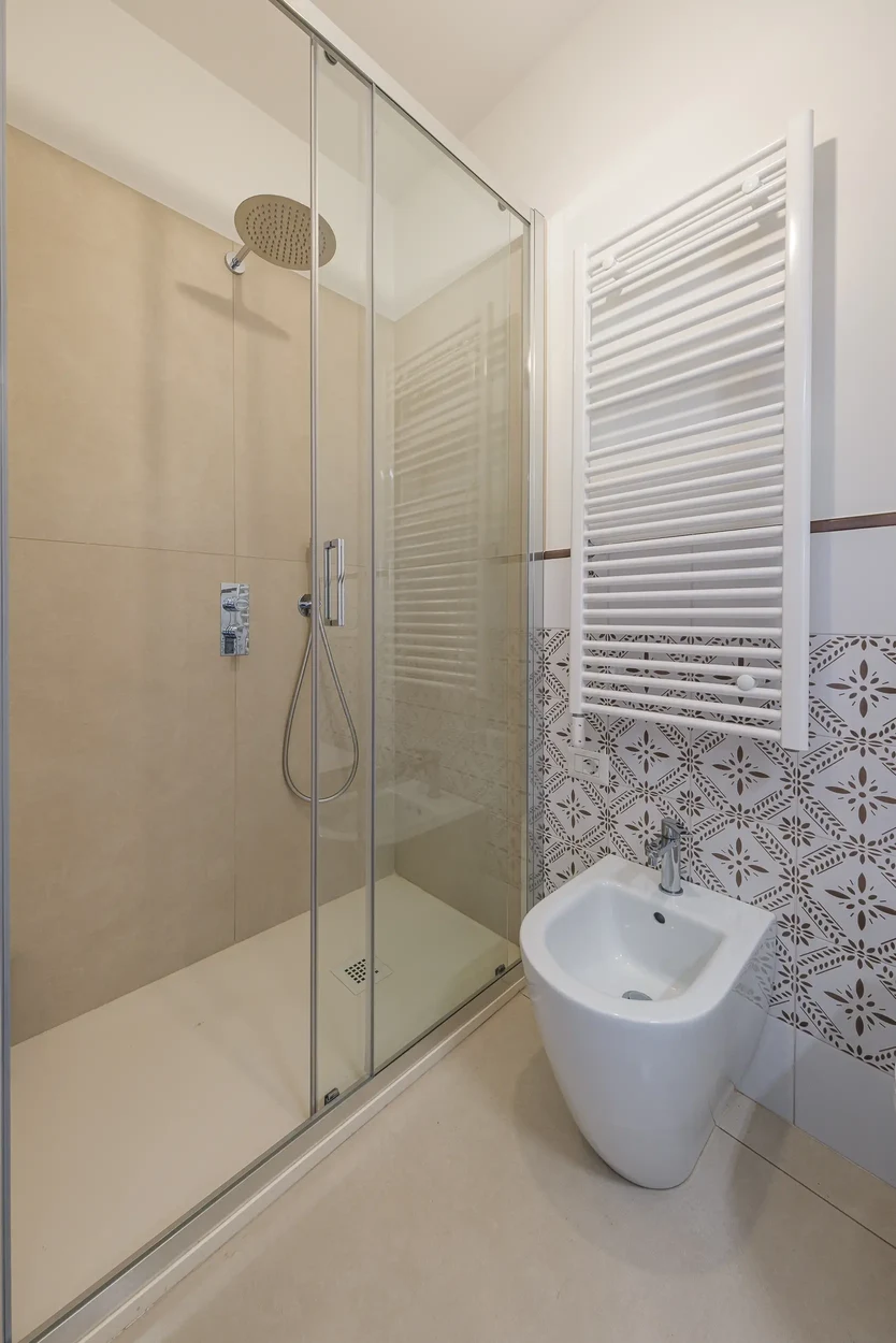 Doccia con piatto bianco, bidet a terra e termoarredo bianco